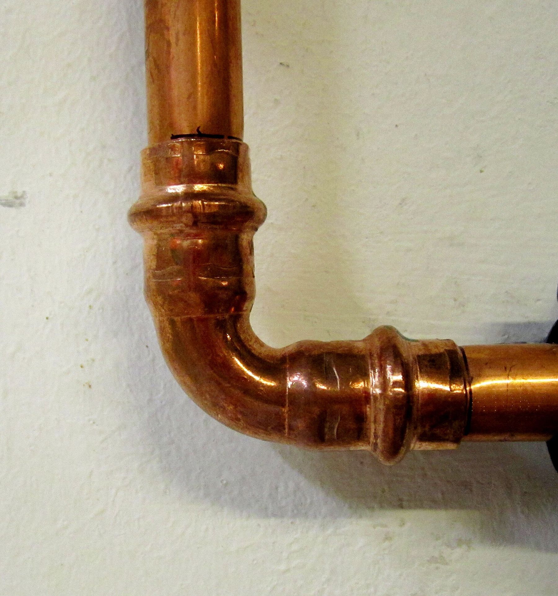 A copper pipe bending through a pressed fitting