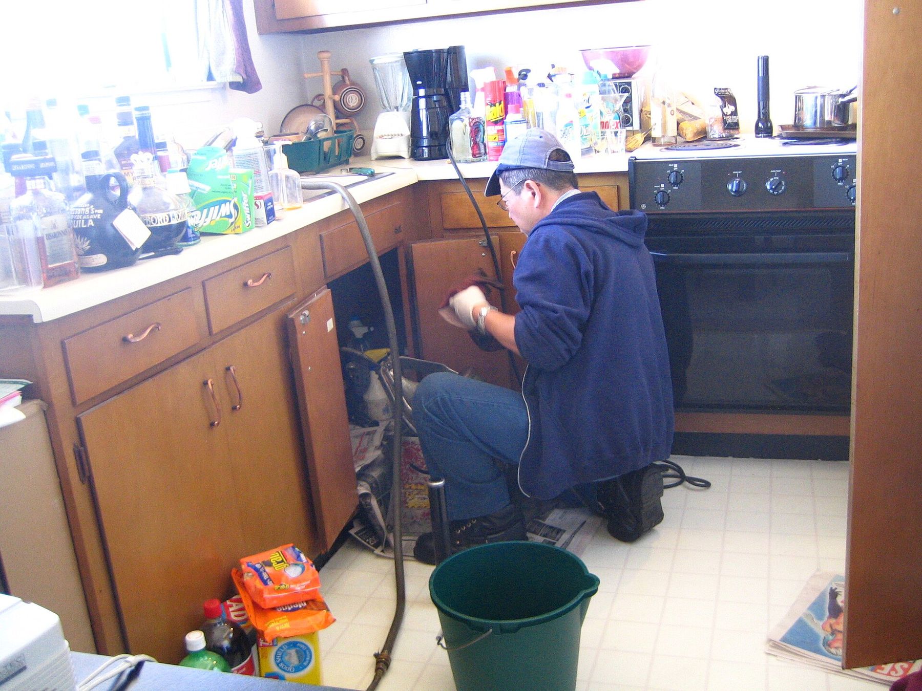 A plumber clearing a drain under a kitchen sink