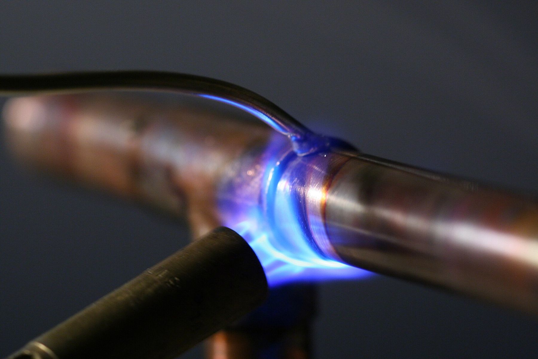 A blue torch flame soldering a joint on a copper pipe