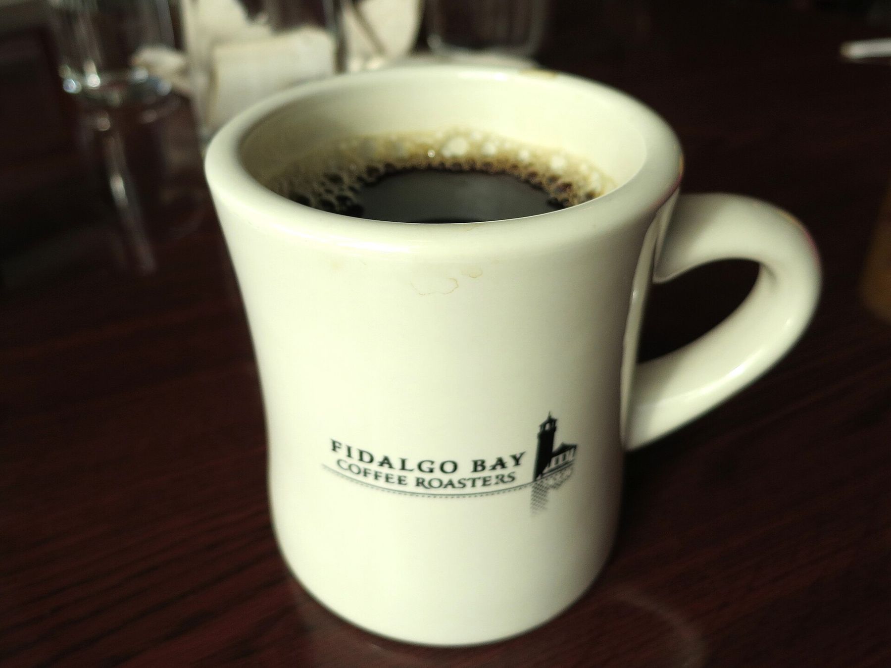 A white mug of black coffee on a diner counter